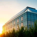 Erleben Sie ein modernes Gebäude mit Photovoltaik Investment auf dem Dach, beleuchtet von Sonnenuntergangslicht.