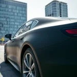 Die matte schwarze Folierung des Fahrzeugs betont seine Eleganz und Modernität in einer urbanen Umgebung.